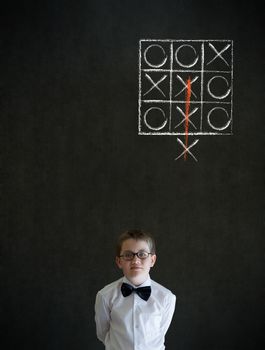 Thinking boy dressed up as business man with thinking out of the box tic tac toe concept on blackboard background