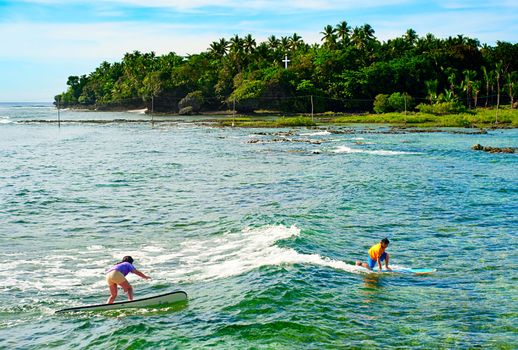 Siargao, Philippines -  May 11, 2013: Young people learning to surf at Cloud 9 surfpoint in Siargao.  In 2011 3.9 million tourists visiting the country.