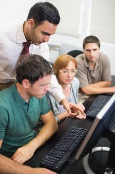 Teacher showing something on screen to mature students in the computer room