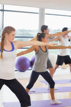 Full length of sporty people stretching hands at yoga class in fitness studio