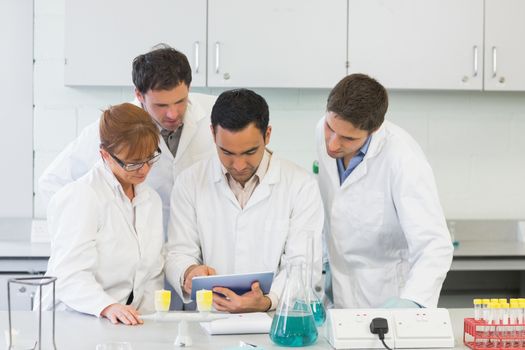 Group of serious scientists using tablet PC in the laboratory