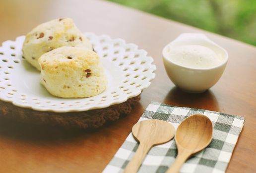 Homemade freshly baked scones with cream and wooden spoon, retro filter effect