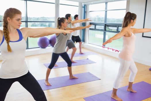 Full length of sporty people stretching hands at yoga class in fitness studio