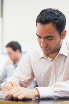 Close up of a mature student taking notes in lecture in college