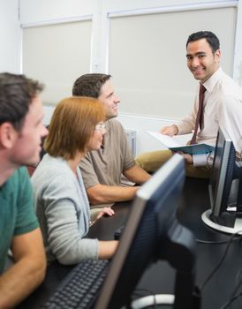 Portrait of a smiling teacher with mature students in the computer room