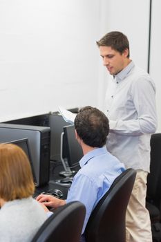 Mature students listening to teacher in the computer room