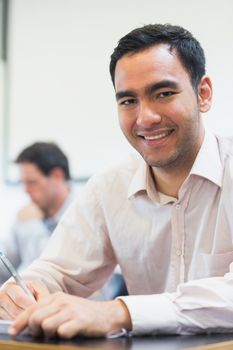 Portrait of a mature student taking notes with others in lecture in college