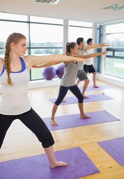 Full length of sporty people stretching hands at yoga class in fitness studio