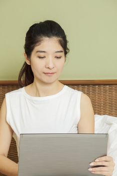 happy young asian woman working with laptop in bedroom