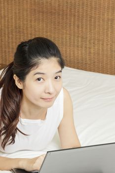 happy young asian woman working with laptop in bedroom