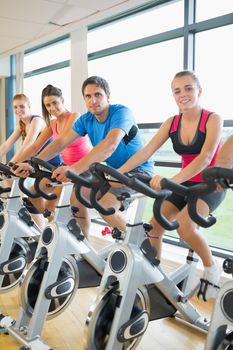 Portrait of four people working out at spinning class in gym