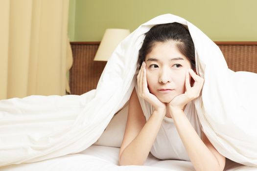 woman lying in bed underneath the quilt and smiling