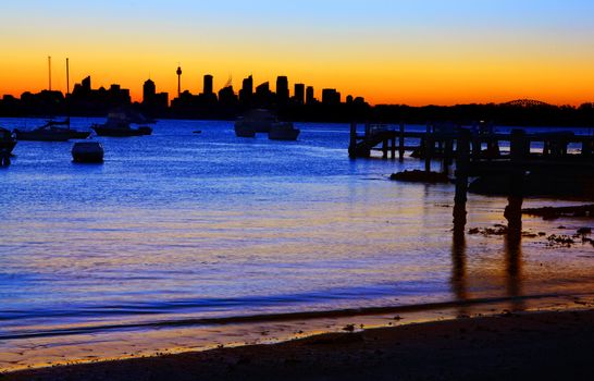 Sydney silhouette, including the tip of the Harbour Bridge from Gibson's Beach, Vaucluse at night.  Some motion blur in water due to exposure time