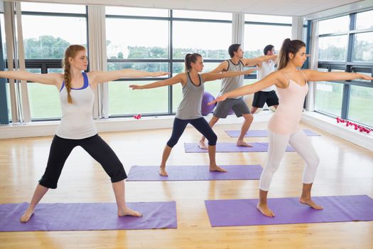 Full length of sporty people stretching hands at yoga class in fitness studio