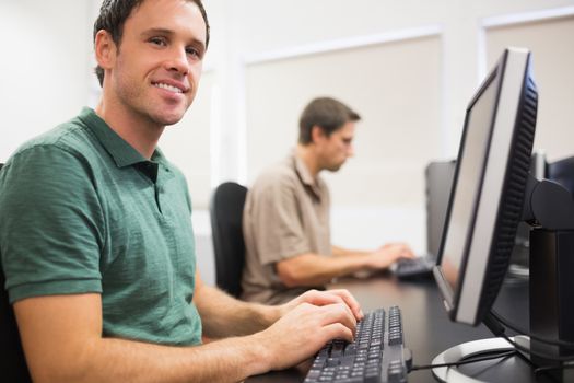 Portrait of a smiling man by other mature student using computers in the computer room