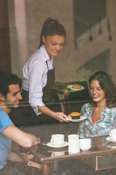 Smiling waitress serving food to a couple in college canteen