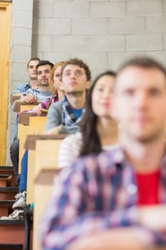 Close up of young students sitting in a row at the college classroom