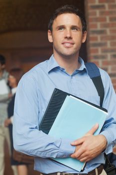 Handsome male mature student posing holding some files in the corridor