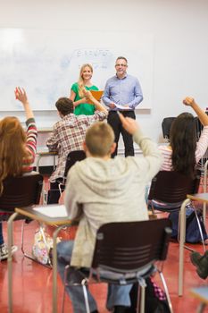 Rear view of students with hands raised in the classroom