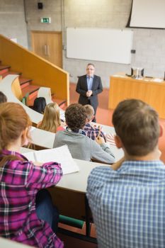 Elegant teacher with students sitting at the college lecture hall