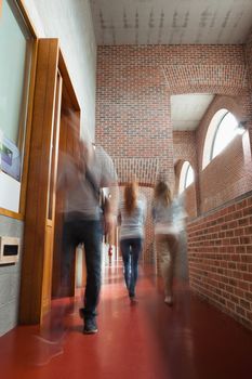 Students walking through hallway away from camera in school