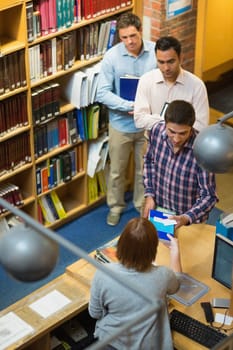 High angle view of mature students at counter in college library