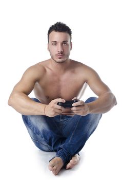 Handsome young man shirtless playing console videogames with joypad in his hands, sitting on the floor, isolated on white
