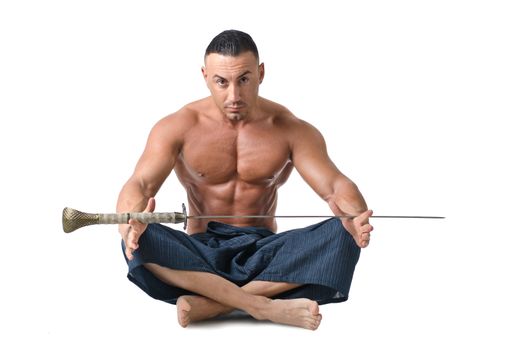 Muscular man sitting on the floor shirtless, with japanese sword on his legs, isolated on white