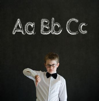 Thumbs down boy dressed up as business man with learn English language alphabet on blackboard background
