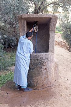 SAHARA DESERT, MOROCCO 20 OCTOBER 2013: Man in traditional clothes drinking water from the well