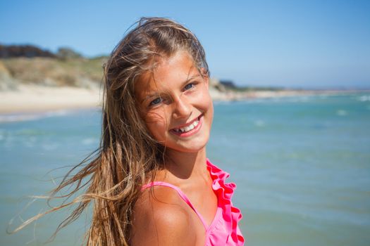 Closeup portrait of young beach girl on blue sea shore in summer vacation