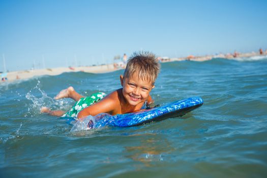 Boy has fun on the surfboard in transparency sea