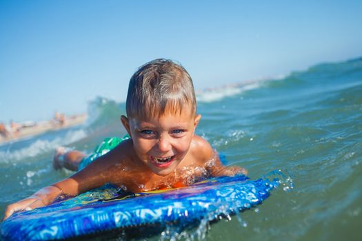 Boy has fun on the surfboard in transparency sea