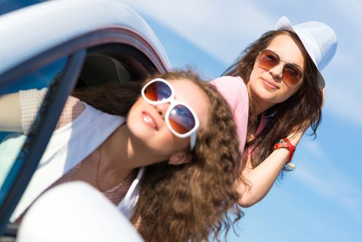 young attractive woman in sunglasses got out of the car window and laugh