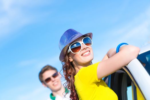 young attractive woman in sunglasses and hat stands next to a car, a close-up portrait