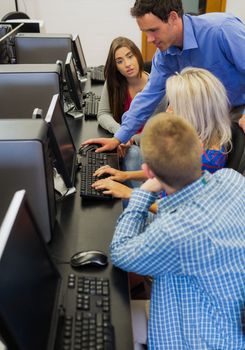 Side view of a teacher explaining to young college students in the computer room