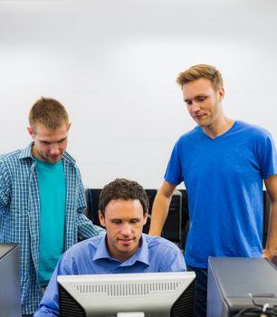 Concentrated teacher and young students using computer in the computer room