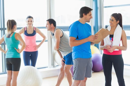 Fit couple with friends standing in background in bright exercise room