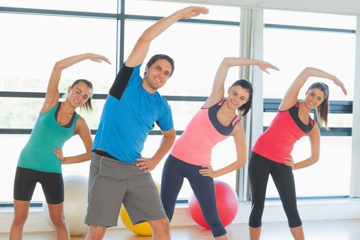 Portrait of smiling people doing power fitness exercise at yoga class in fitness studio