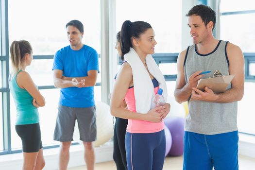 Fit couple with friends standing in background in bright exercise room