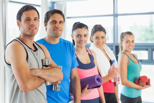 Portrait of a group of fitness class standing in row at a bright exercise room