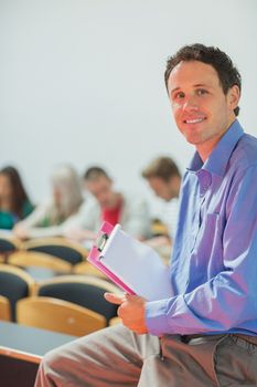 Portrait of a smiling teacher with young college students in the classroom