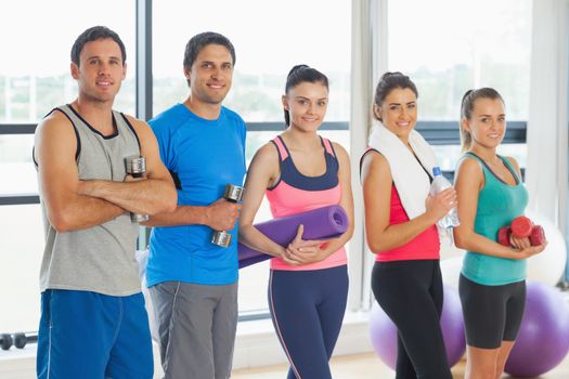 Portrait of a group of fitness class standing in row at a bright exercise room