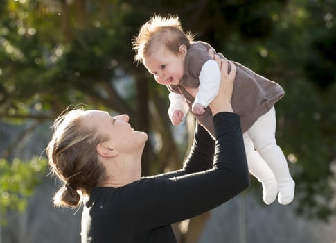 Young mother playing with sweet baby girl outdoors