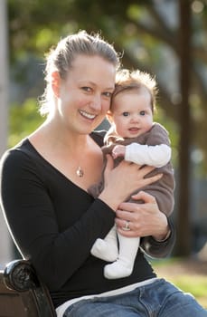 Young mother playing with sweet baby girl outdoors