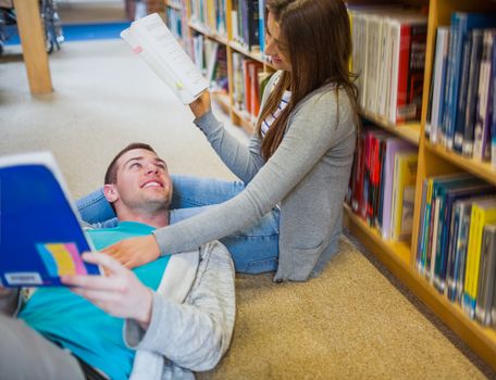 Relaxed young romantic couple with books at the library aisle