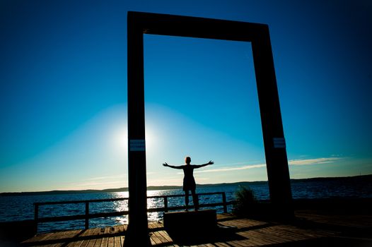 Young Woman Silhouette with open arms to the sea on Summer Sunset