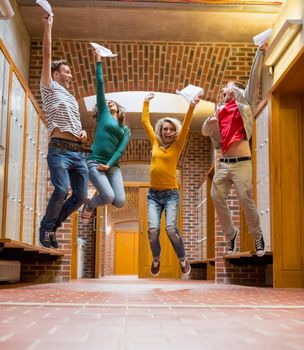 Full length of a group of students jumping in college corridor