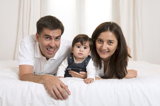 Young couple mother father and baby girl laying on bed isolated portrait