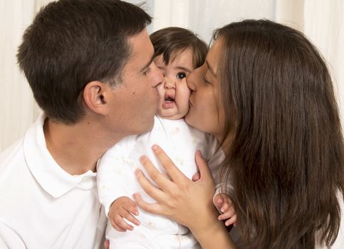Mother and Father Kissing their Baby Girl
